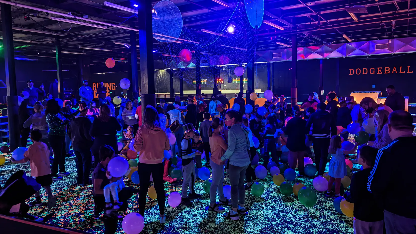 Large crowd celebrating with balloons during a neon blacklight event at Fun Slides.