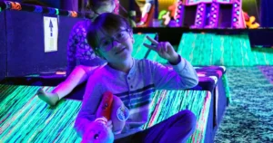 Kids laughing and gliding on carpet skates across a glowing blacklight ramp at Fun Slides in Pittsburgh
