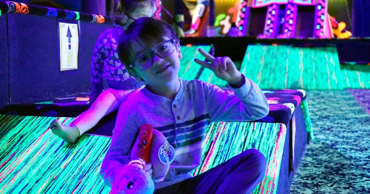 Kids laughing and gliding on carpet skates across a glowing blacklight ramp at Fun Slides in Pittsburgh